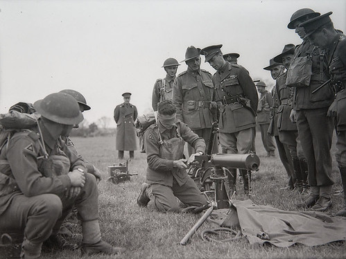 King George VI inspects Australian soldier assembling Vickers machine gun whilst blindfold — related to accessories